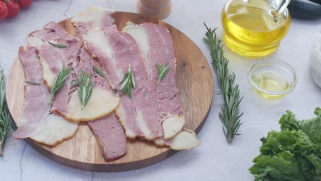 sliced bacon with rosemary on wooden board