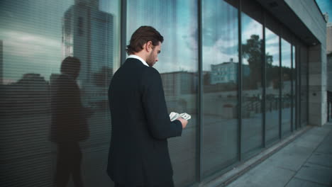 businessman with money walking on street. male professional counting money