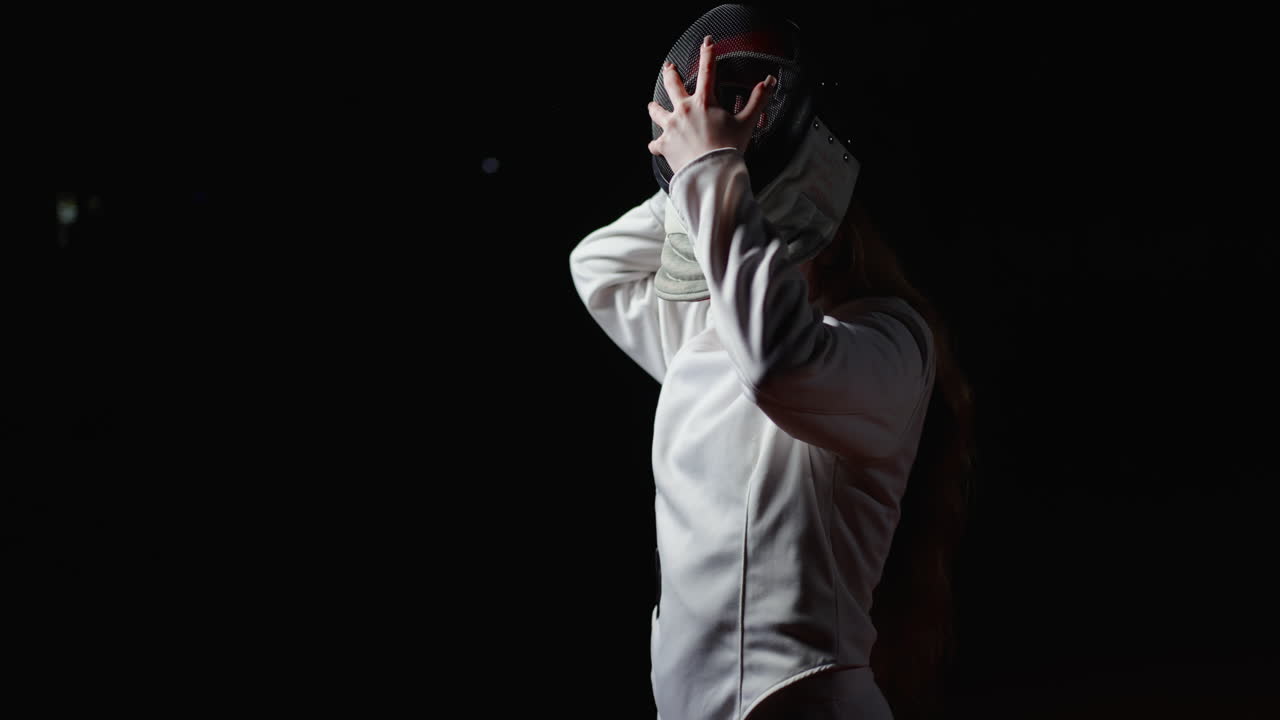 Female fencer in a white uniform with a mask on, looking determined