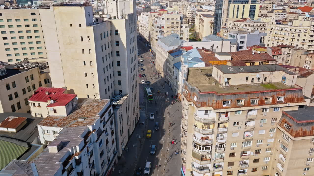 Vista aérea con dron de una carretera del centro con tráfico y gente caminando. Día soleado
