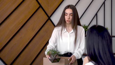 worried and sad young woman talking with her co-worker and saving her stuffs on an empty box