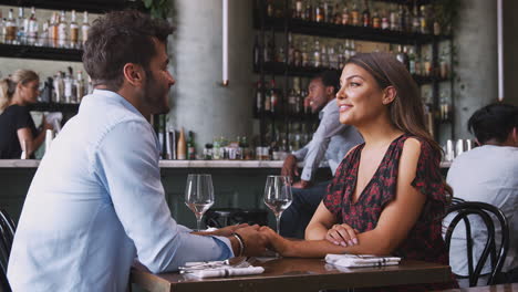 female waitress with digital tablet taking order from romantic couple sitting at restaurant table
