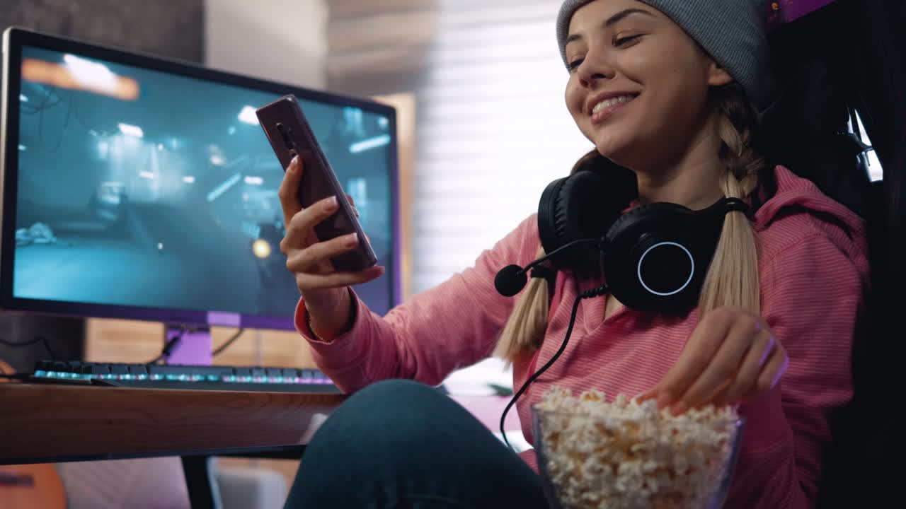 una joven usa el teléfono mientras mira las redes sociales y come palomitas de maíz después de jugar juegos de computadora.