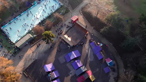 aerial orbit of a skate park ramp with people skating on it, parque araucano, santiago, chile