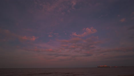 tiempo lapse de la mar de wadden el cielo de puesta de sol en hooksiel, alemania del norte con nubes en movimiento y un barco de contenedores