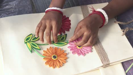 old woman's hand doing craftwork on jute cloth with colorful paper strips