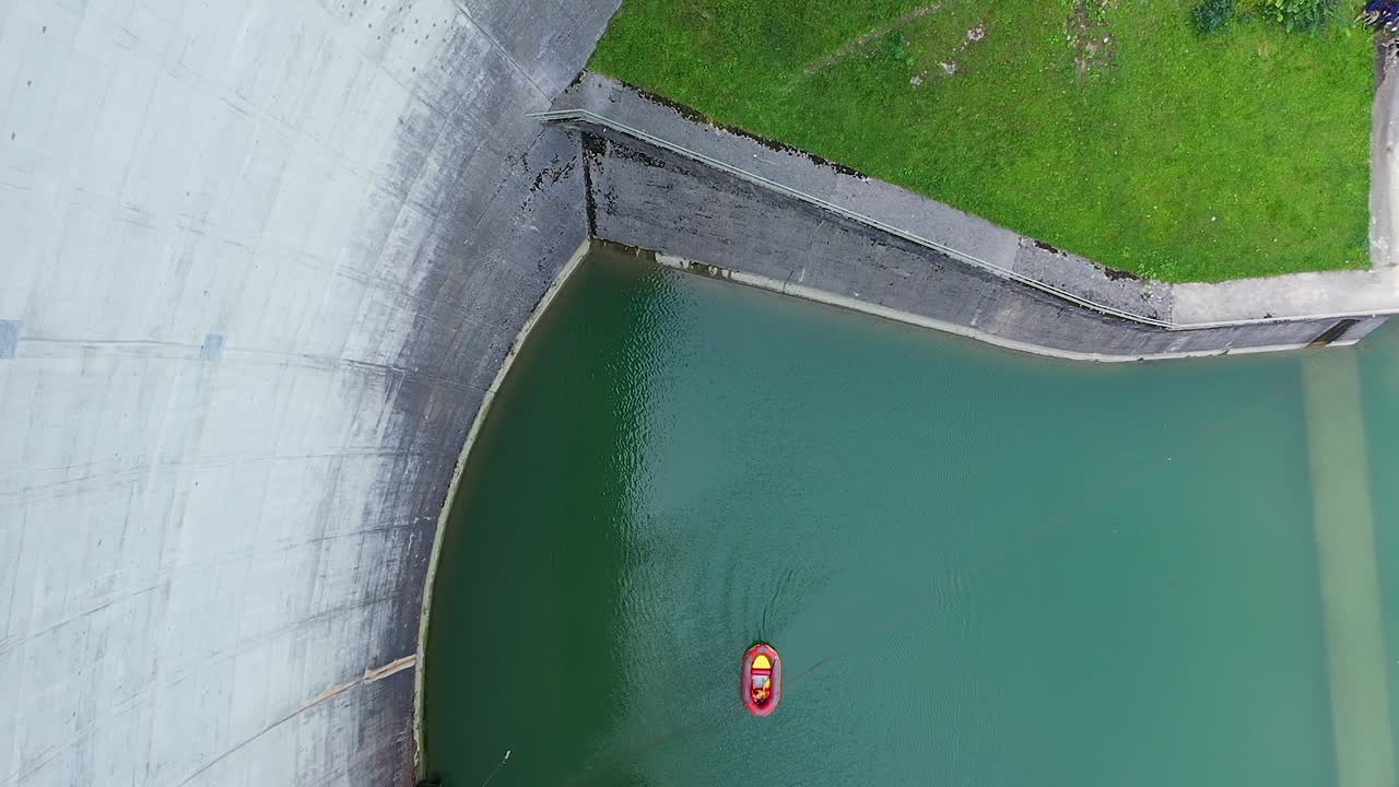 Aerial drone view of young girl hang swinging the bungee jumping cord off a 50m high dam platform
