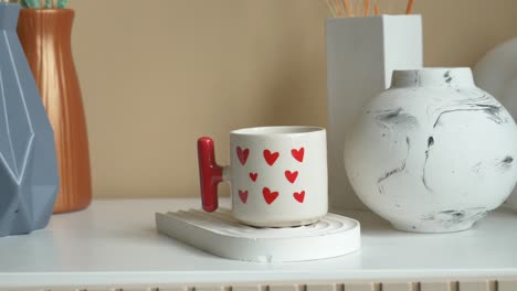 taza blanca con corazones rojos en el estante