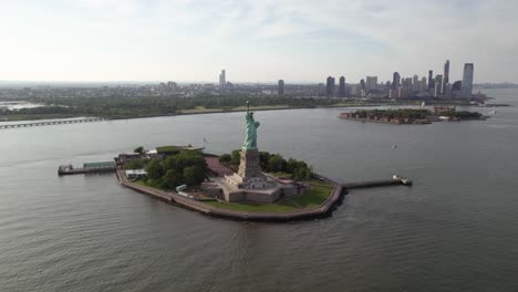 La-Estatua-De-La-Libertad-De-La-Dama-Y-La-Isla,-En-La-Soleada-Nueva-York,-Ee.uu.---Ascendente,-Antena-Inclinada