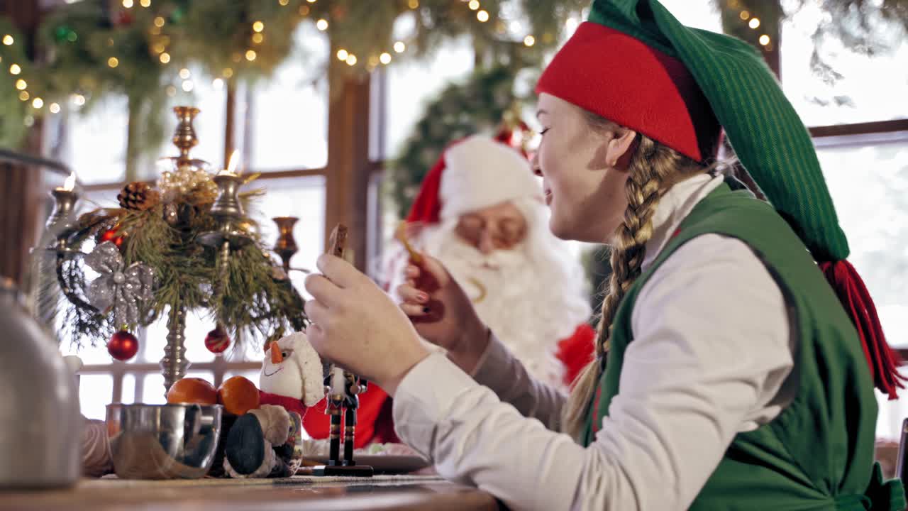 Elf eating cookies. Portrait of girl elf eating cookies at table