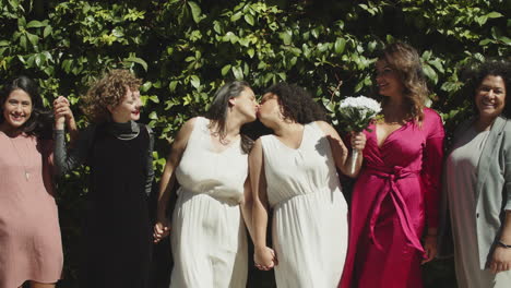 slider shot of lesbian brides taking photo with friends