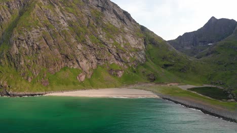 Aerial-shot-of-remote-Lofoten-Sandvika-beach-in-Noway-surrounded-by-steep-cliffs