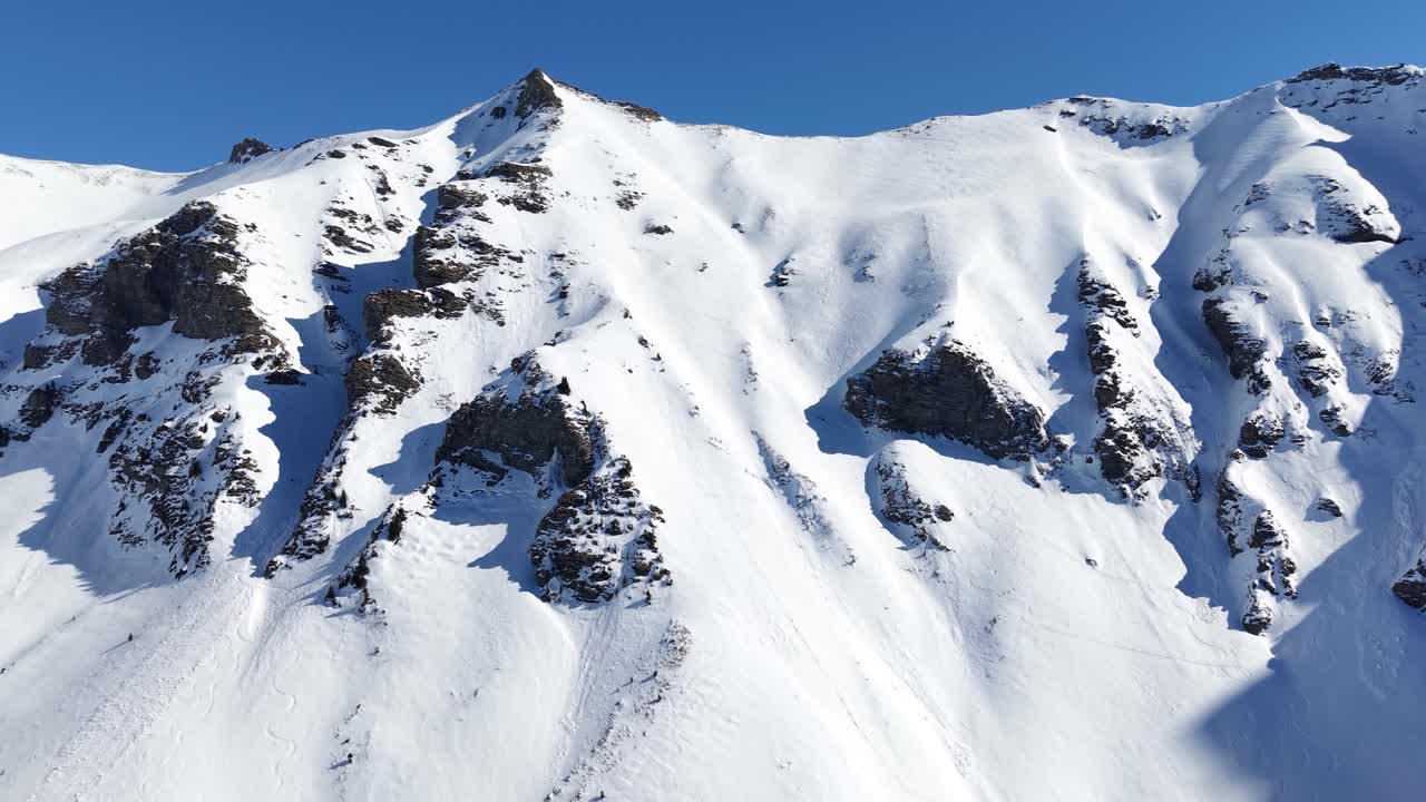 Drone climbing swiss mountain face on a sunny winter day at Diemtigtal.