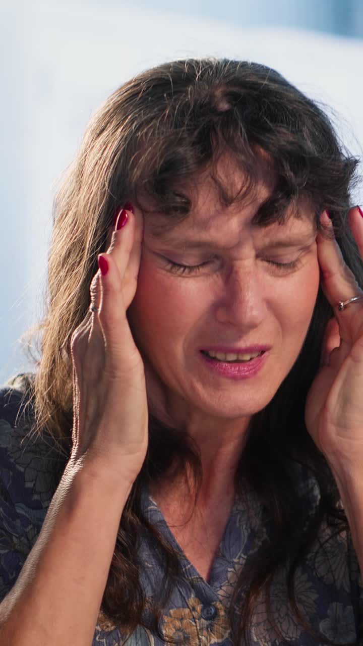 Vertical Video Senior woman at checkup deals with a painful headache and asks for advice