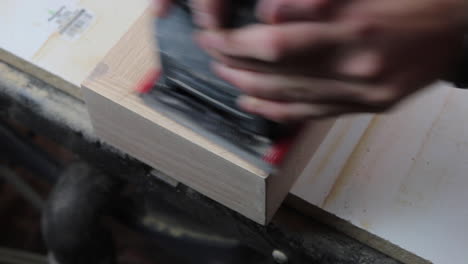 finish sanding the wood filler on wooden floating shelves in preparation to be stained and hung in a remodeled bathroom