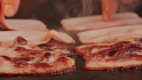 Cooking bacon slice for burgers on the grill close-up macro. The chef in kitchen of the restaurant making cutlets for smash burgers - smash burger beefsteak. Fast and street food concept. High quality 4k footage
