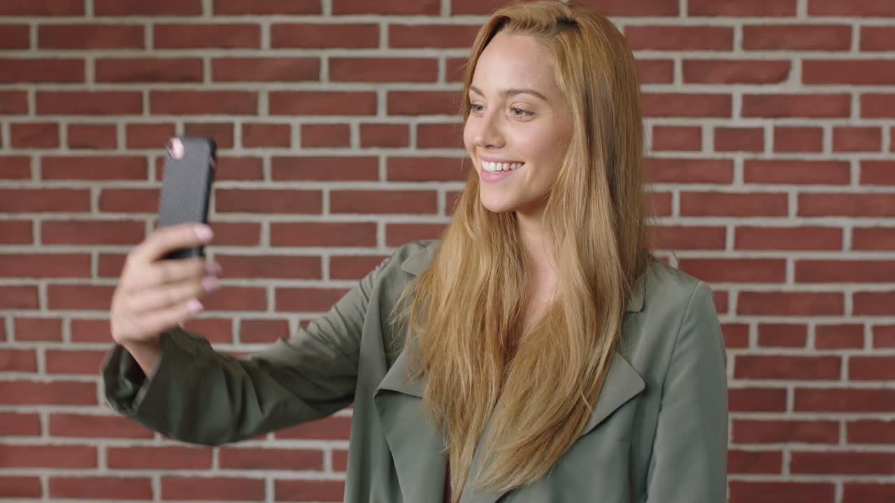 retrato de una joven rubia usando un teléfono inteligente tomando una foto selfie sonriendo