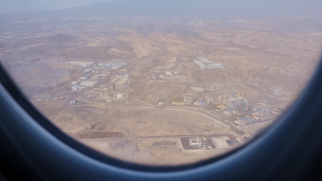 Aerial shot from plane over Tenerife coastline reveals industry and mountains