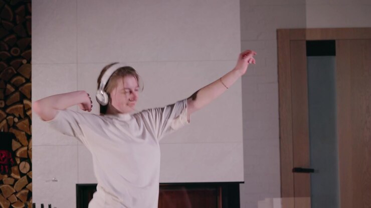Woman Dancing with Headphones in Front of Fireplace