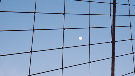 majestic moon in dark blue dawn sky, view through cables of brookly bridge