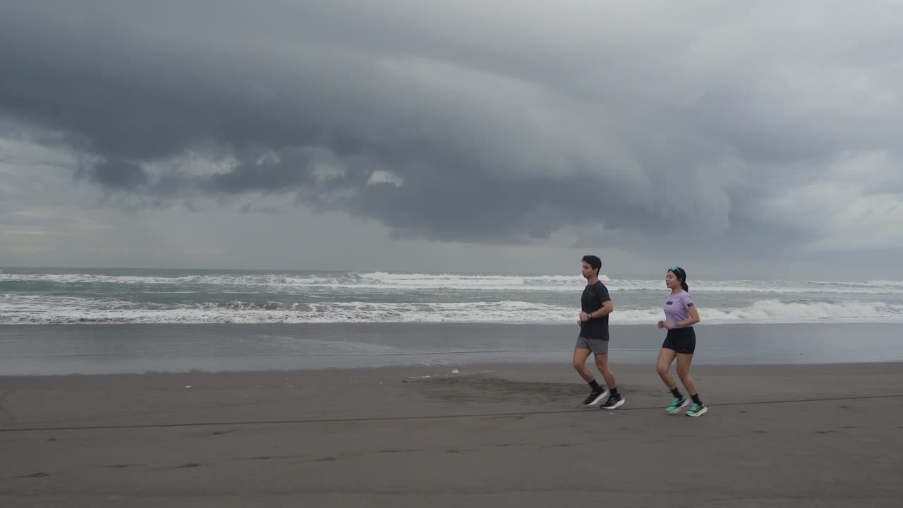 Couple Running on the Beach During Cloudy Weather
