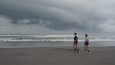 couple running on the beach during cloudy weather