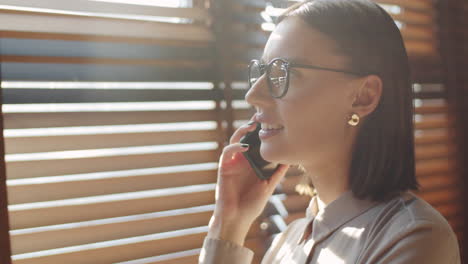 Businesswoman-Talking-on-Phone-near-Window-in-Office