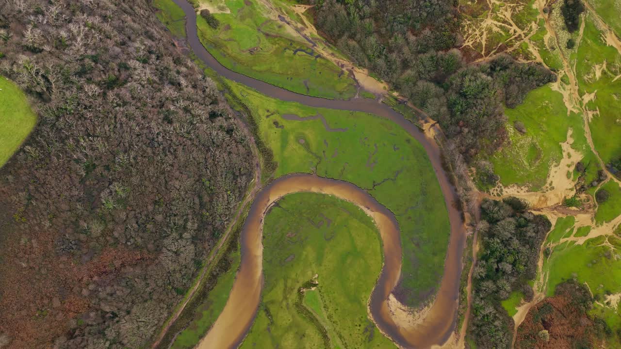mirando hacia abajo en el río pysgodlyn serpenteando a través del paisaje verde exuberante en la bahía de tres acantilados