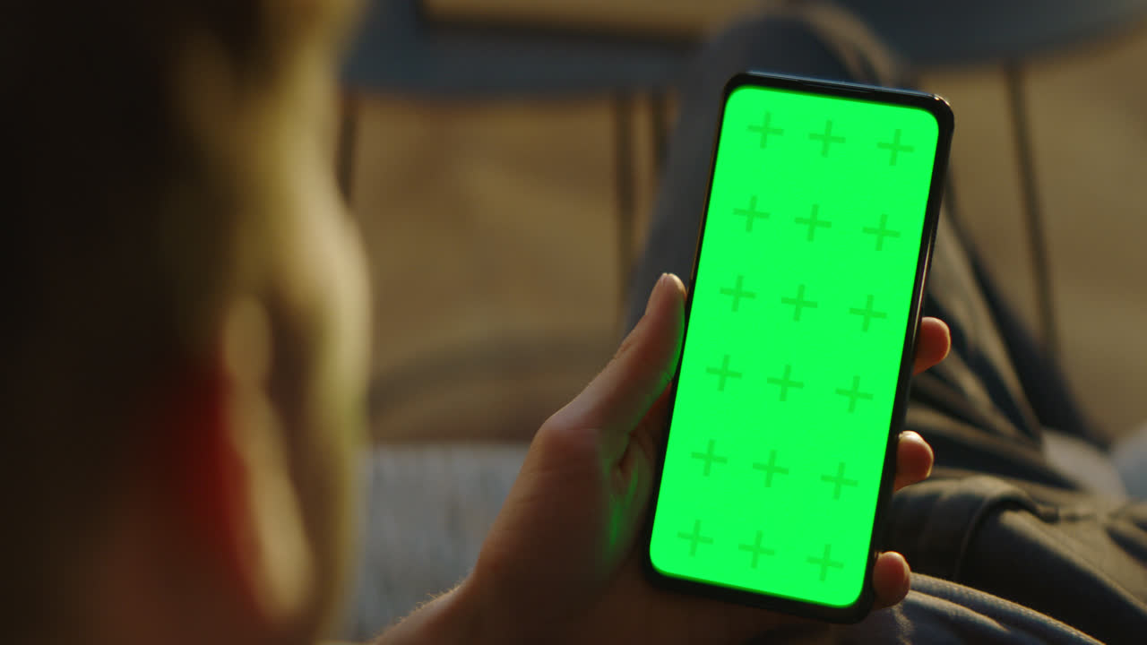 초록색 화면의 스마트폰을 들고 있는 사람