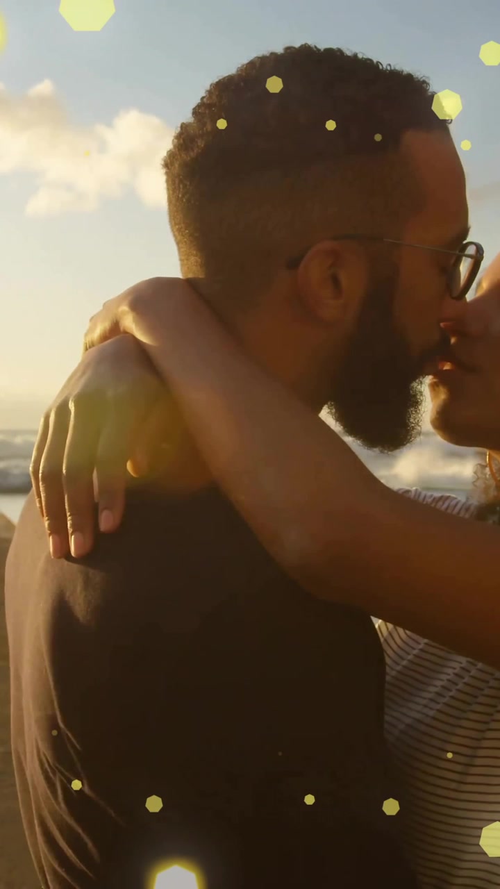 Animation of spots of light over happy diverse couple embracing by sea