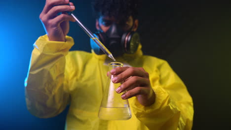 chemist with the gas mask and the protective suit in hazmat suit handling hazardous chemicals in a sterilised container