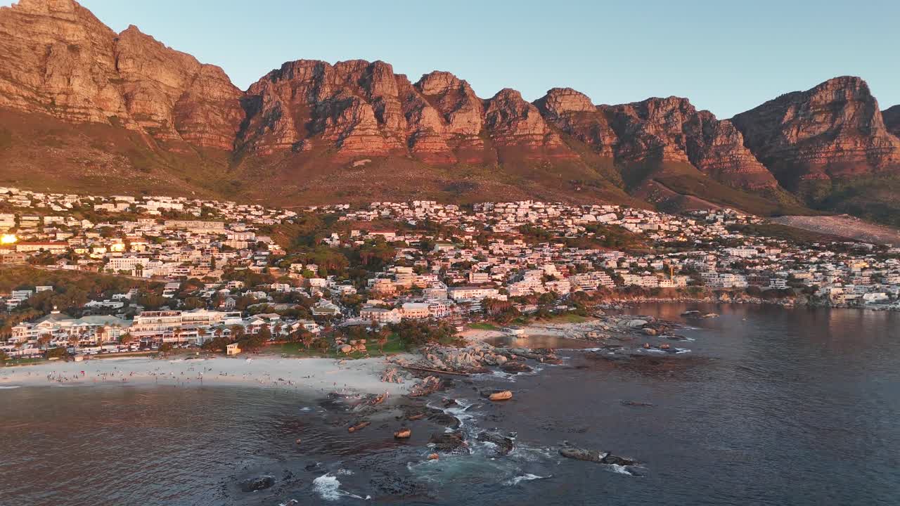 south africa cinematic drone footage of Lion’s Head and Atlantic coastline at sunset aerial shot over Camps Bay beach with dramatic lighting and cityscape in the background