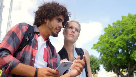 hombre y mujer buscando dirección usando teléfono móvil
