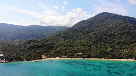 Aerial-view-overlooking-blue-sea,-beaches-and-the-jungle-on-the-coast-of-Tayrona,-Colombia---dolly,-drone-shot