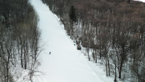 the aerial footage with slow zoom in captures the exciting movements of a snowboarder carving down the slopes of yabuli resort, surrounded by stunning scenery