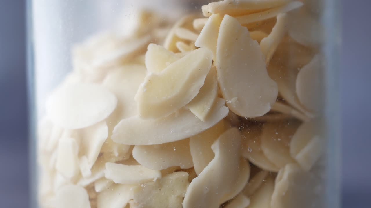 cerca de los copos de nueces de almendra en un frasco