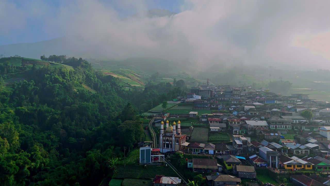 vista aérea de una hermosa aldea con una montaña de niebla en el fondo