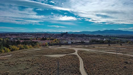 Gewundene-Wege-Auf-Dem-Land,-Die-Zur-Historischen-Stadt-Avila,-Spanien,-Unter-Einem-Weiten-Blauen-Himmel-Führen,-Luftaufnahme