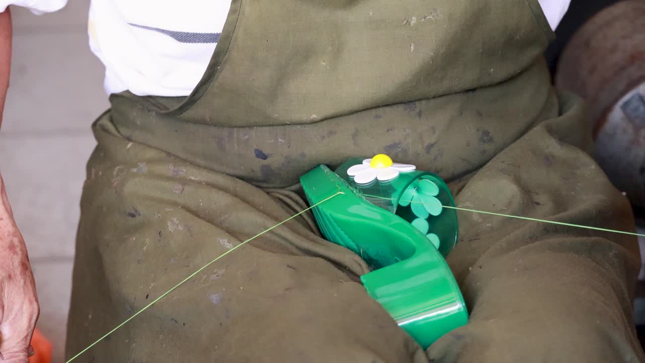 Hands skillfully stitch a green shoe with floral details, showcasing traditional craftsmanship in a well-lit workshop