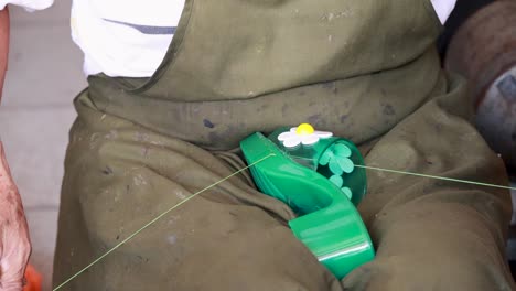 hands skillfully stitch a green shoe with floral details, showcasing traditional craftsmanship in a well-lit workshop