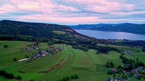 aerial drone forward moving shot over village houses beside a fjord surrounded by mountain range in norway on a cloudy day