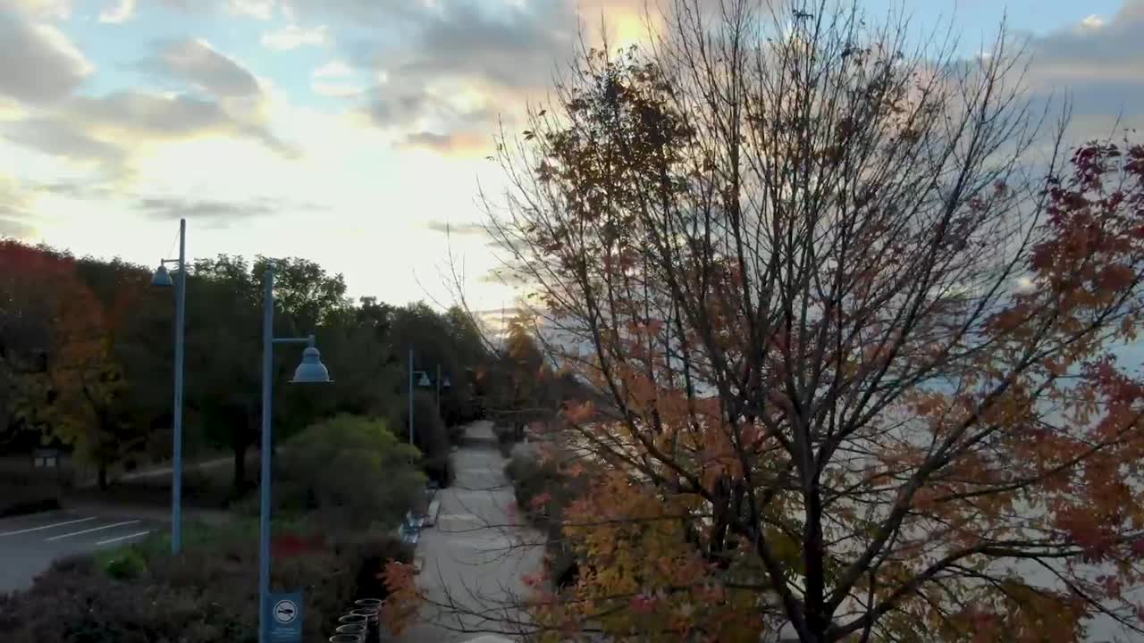 일출 때 온타리오 호수의 항구를 드러내는 보도 위로 날아가는 드론