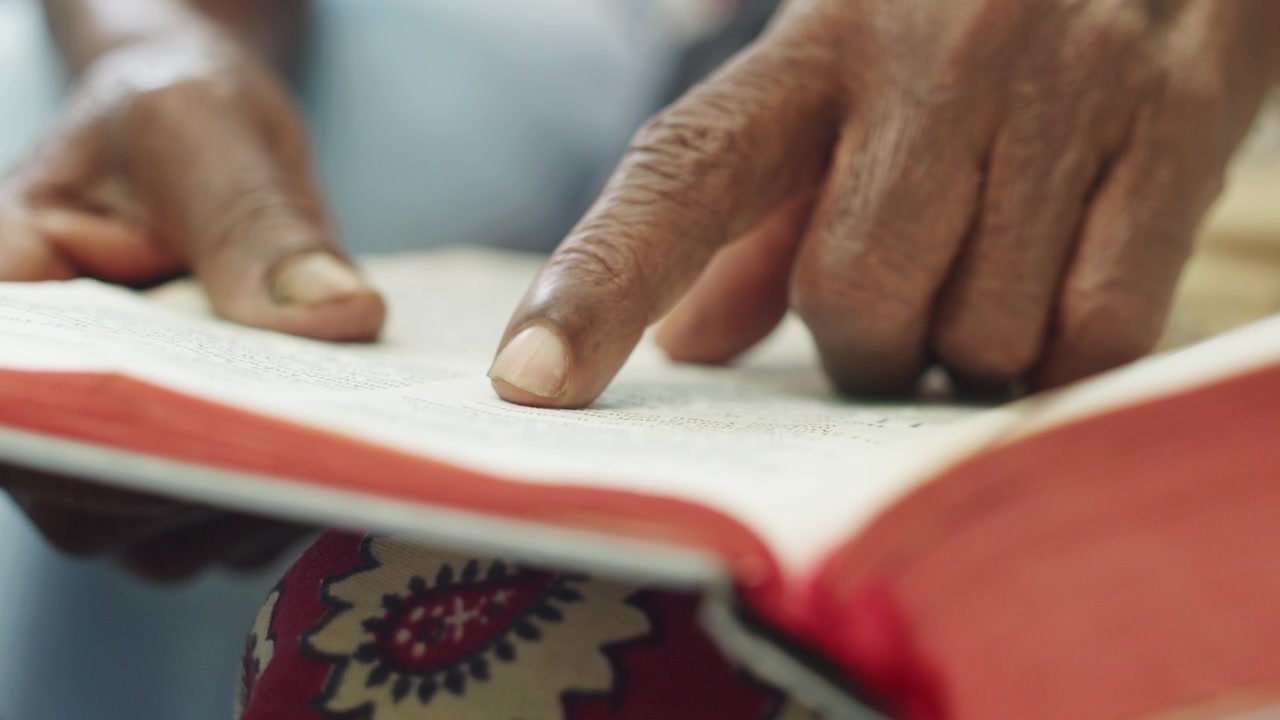 Africká žena čtoucí Bibli a ukazující prstem.