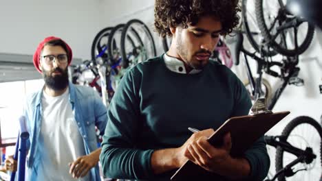 mechanic writing on clipboard in workshop