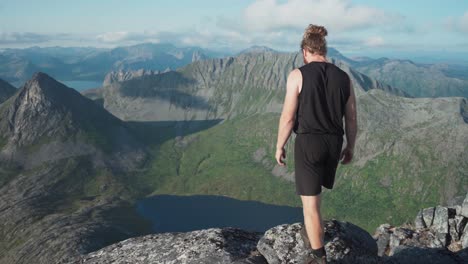 Hombre-Caminando-Sobre-El-Pico-De-La-Montaña-Lonketinden-Con-Vistas-Al-Paisaje-Noruego-En-Senja,-Noruega