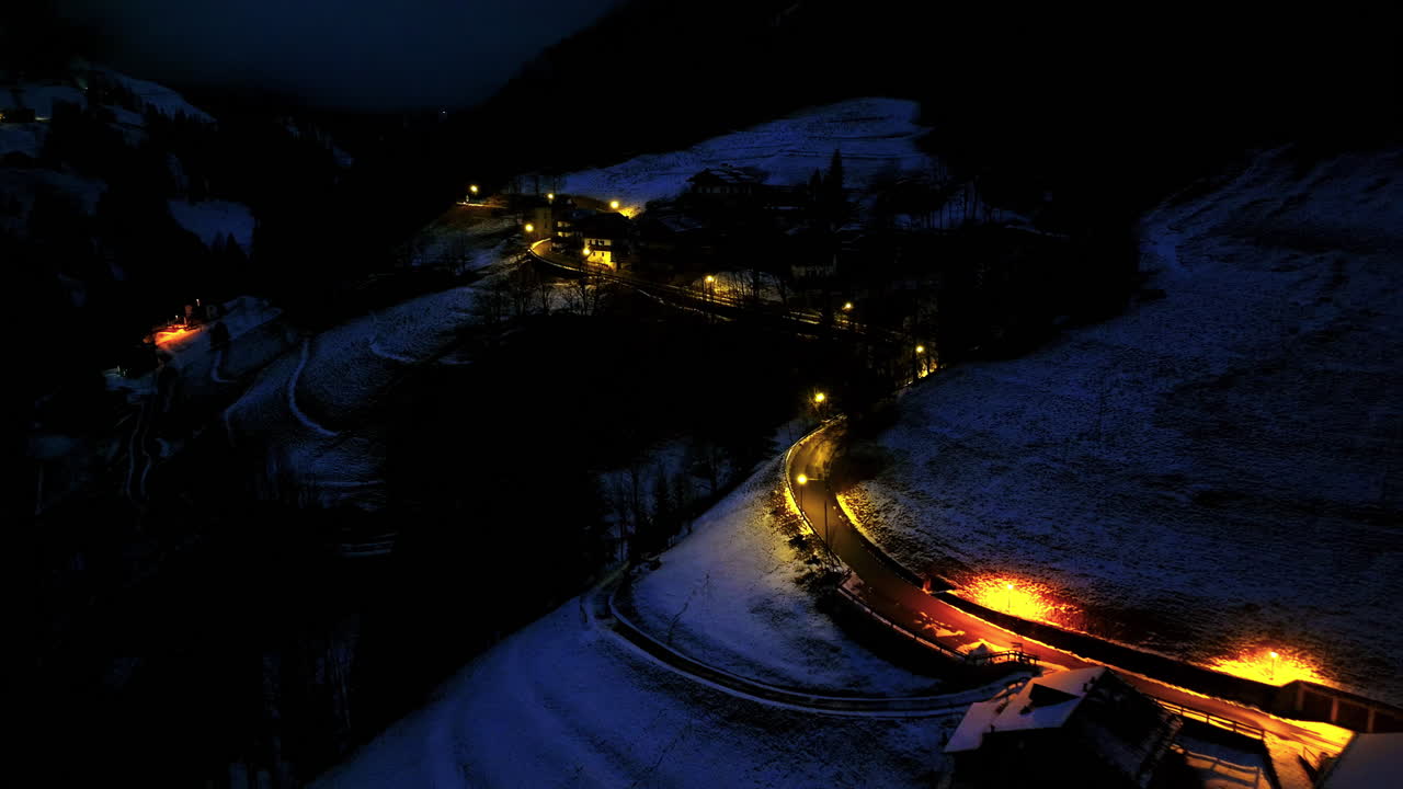 Aerial drone view of a human settlement, in the Dolomites, Italy, illuminated in the evening