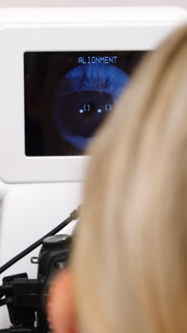 una optometra examinando a un paciente joven en coreometría