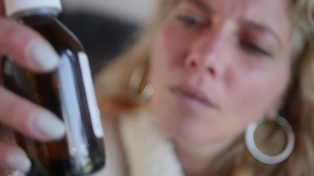 아픈 여자가 병 속의 액체 약을 흔든다