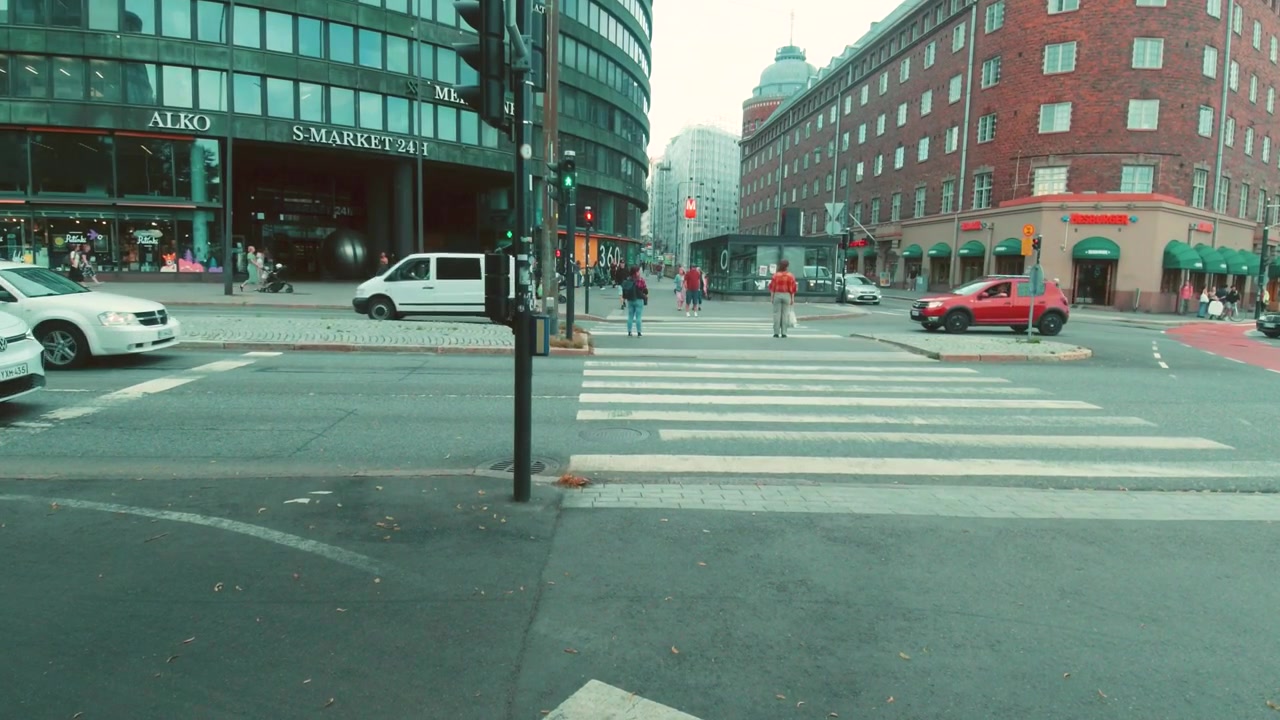 Helsinki Downtown Busy Intersection with Road Traffic and People at Zebra Crossing. Establishing Shot of City Life with Buildings in Background.