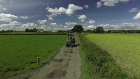 aerial drone shot of farmer driving a tractor in ireland